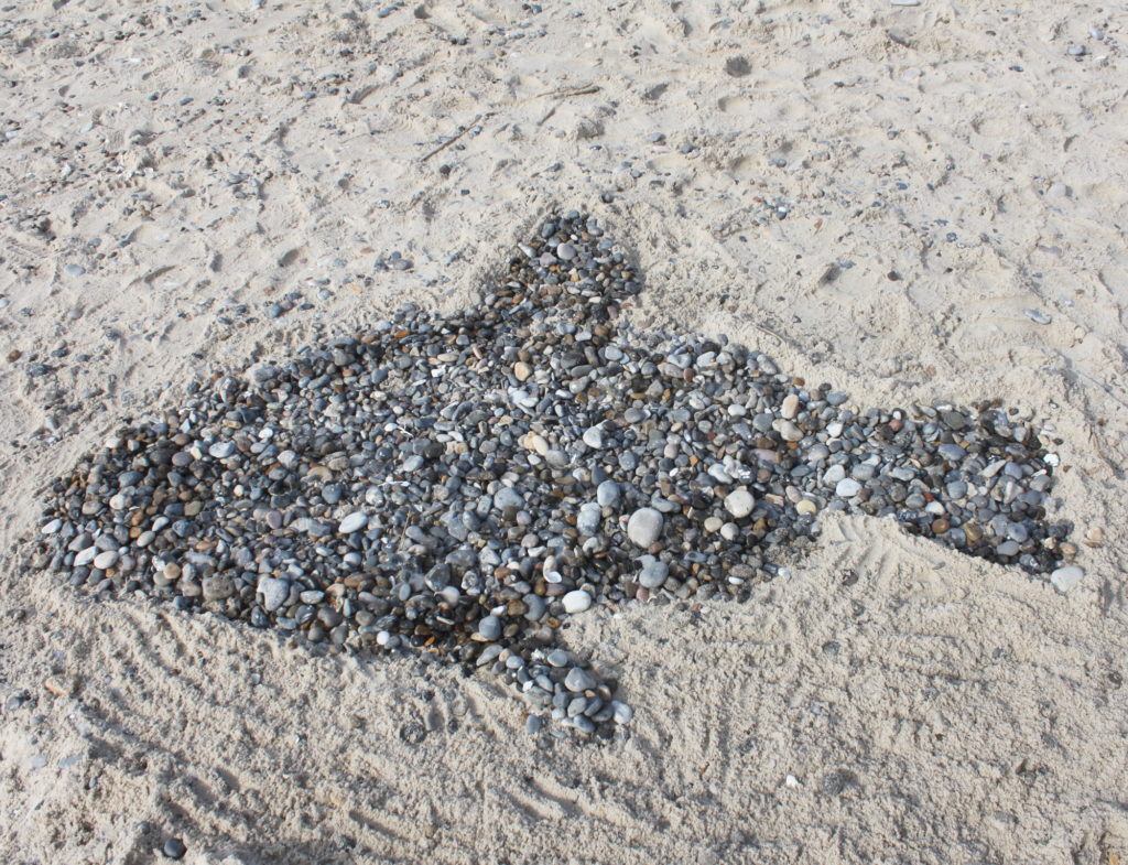 Fisch am Strand gelegt aus Steinen.