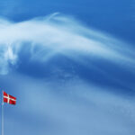 Leuchtturm und die dänische Flagge vor blauem Himmel