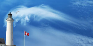 Leuchtturm und die dänische Flagge vor blauem Himmel