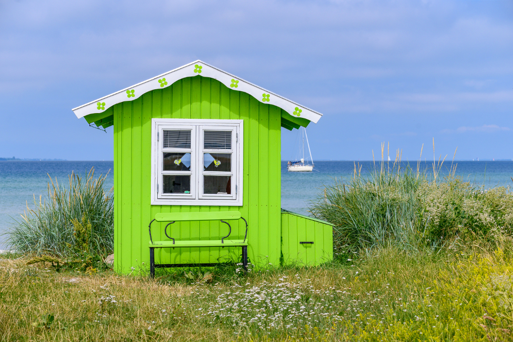 Foto von einem knallgrünen Badehaus an der Küste von Dänemark