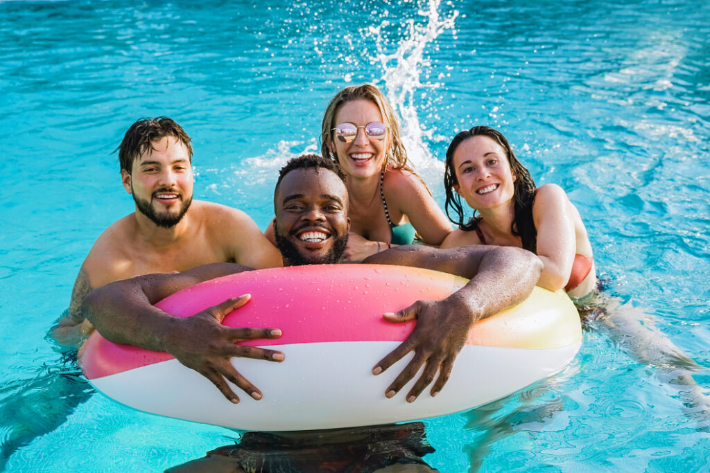 Foto von vier jungen Menschen, die gemeinsam in einem Swimmingpool im Ferienhaus in Dänemark schwimmen und lachen 