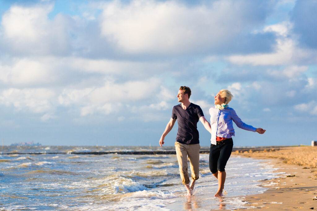 Laufendes Pärchen mit guter Laune am Strand in Dänemark zu Himmelfahrt oder Pfingsten