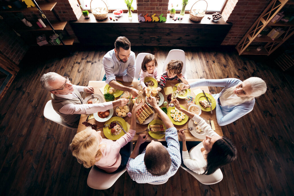 Draufsicht auf einen festlich gedeckten Tisch zu Ostern, an dem die ganze Familie mit mehreren Generationen sitzt